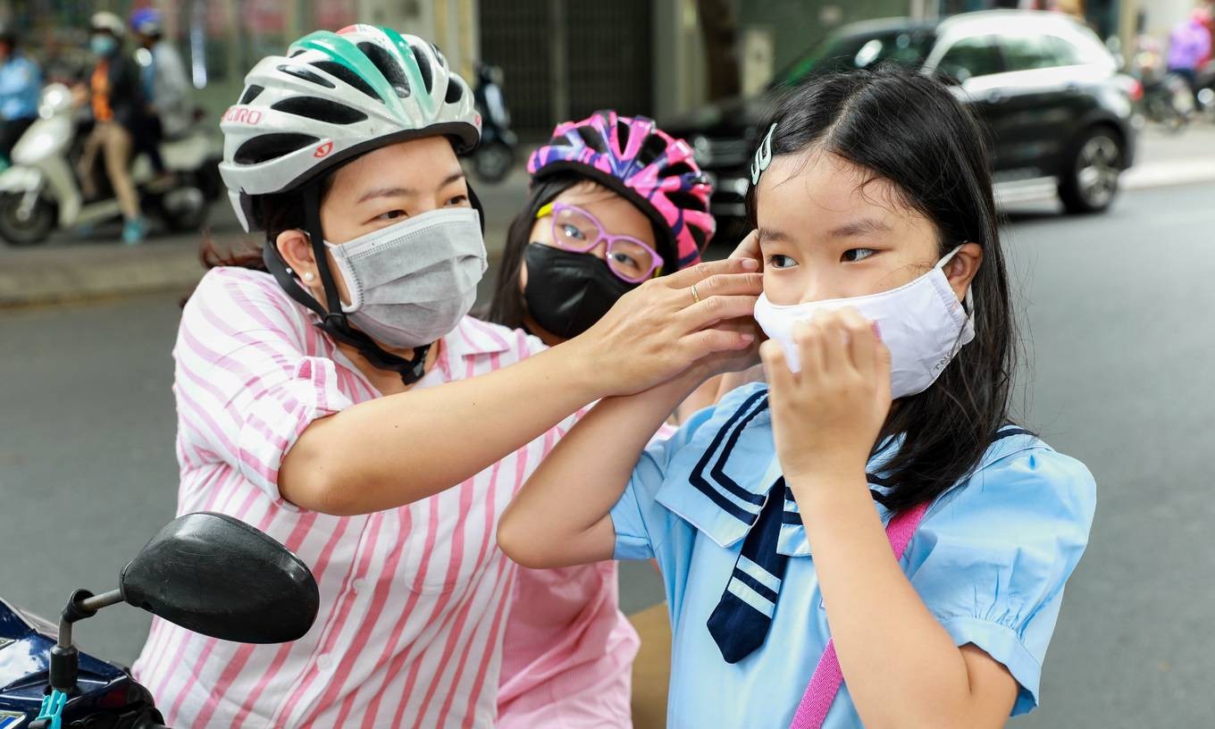 A mother helps her daughter adjust a face mask before she attends classes at a primary school in Ho Chi Minh City's District 1, May 2020. Photo by VnExpress/Quynh Tran.